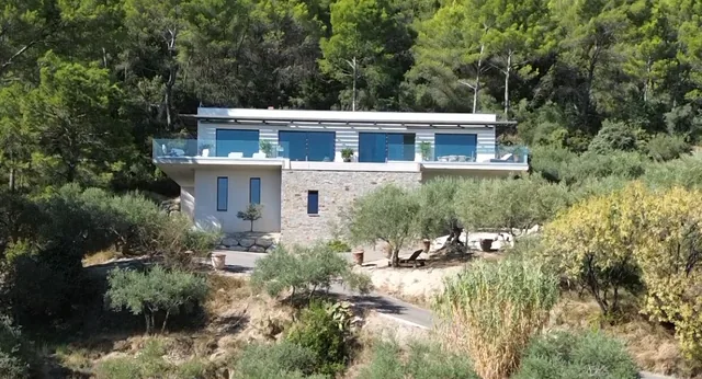 La terrasse filante du niveau de vie, protégée d’un garde-corps en verre, posée sur le socle de pierre.